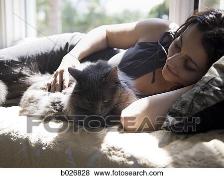 Stock Photo - woman on a window bench with her cat. Fotosearch