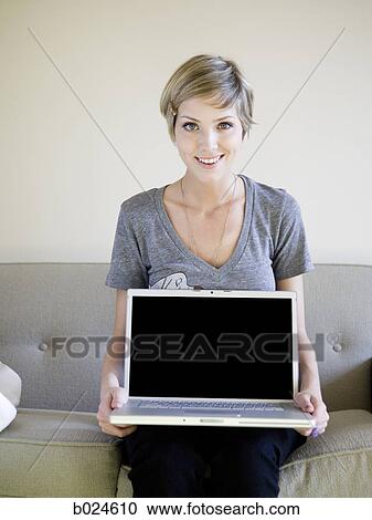 Stock Image - woman on the couch using a laptop. Fotosearch