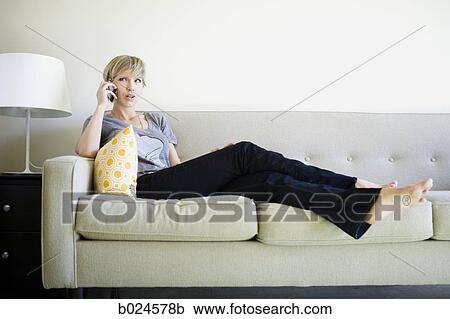 Stock Image - woman on the couch using cell phone. Fotosearch