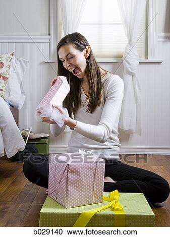 woman opening presents with a surprised look on her face View Large Photo Image Stock Image - woman opening presents with a surprised look on her face. Fotosearch