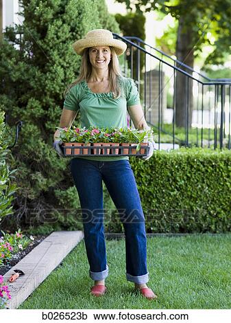 Stock Image - woman planting flowers in her garden. Fotosearch