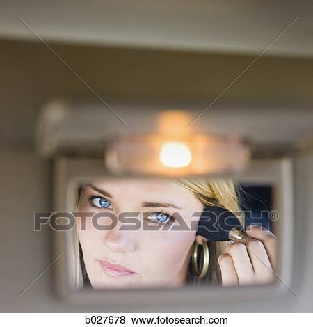 woman putting on makeup in the visor mirror of the car View Large Photo Image Stock Photo - woman putting on makeup in the visor mirror of the car. Fotosearch