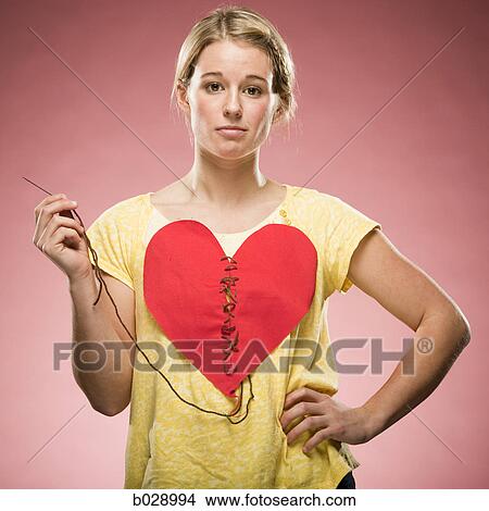 Picture - woman sewing up her own heart. Fotosearch