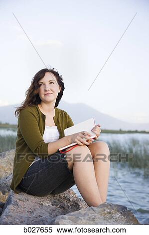 woman sitting by a lake with a notebook View Large Photo Image Stock Photography - woman sitting by a lake with a notebook. Fotosearch