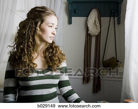 Stock Photo - woman sitting in her bedroom next to a window. Fotosearch