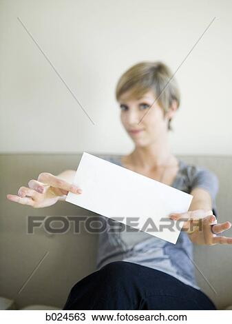 woman sitting on a couch holding up an envelope View Large Photo Image Stock Image - woman sitting on a couch holding up an envelope. Fotosearch