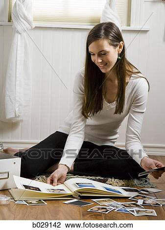 Stock Image - woman sitting on the floor in her room scrapbooking. Fotosearch