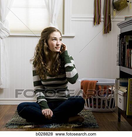 woman sitting on the floor of her bedroom on her cell phone View Large Photo Image Stock Photo - woman sitting on the floor of her bedroom on her cell phone. Fotosearch