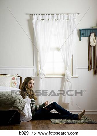 Stock Photography - woman sitting on the floor of her bedroom writing in a journal. Fotosearch