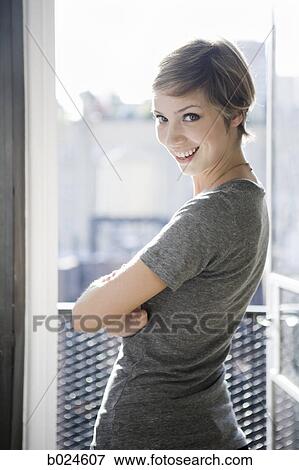 Stock Photo - woman standing in front of an open window. Fotosearch