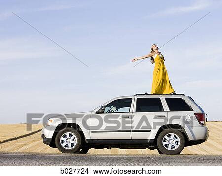 woman standing on the roof of her car on the side of the road View Large Photo Image Picture - woman standing on the roof of her car on the side of the road. Fotosearch