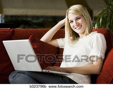 Stock Image - woman using a laptop on a sofa. Fotosearch