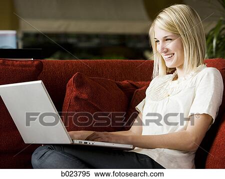 Stock Photography - woman using a laptop on a sofa. Fotosearch