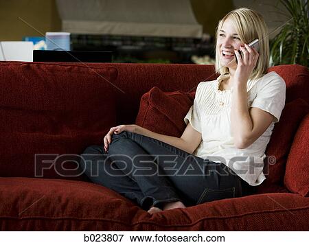 woman using her cell phone on a red sofa View Large Photo Image Stock Photo - woman using her cell phone on a red sofa. Fotosearch