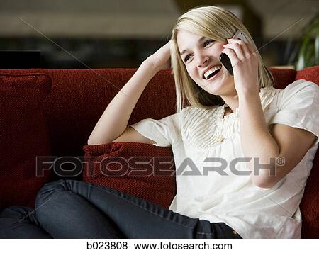 woman using her cell phone on a red sofa View Large Photo Image Stock Photo - woman using her cell phone on a red sofa. Fotosearch