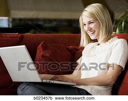 Stock Image - woman using laptop on the couch. Fotosearch