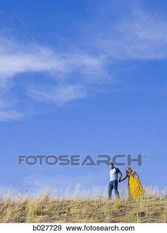 young couple holding hands on a ridge View Large Photo Image Stock Photo - young couple holding hands on a ridge. Fotosearch