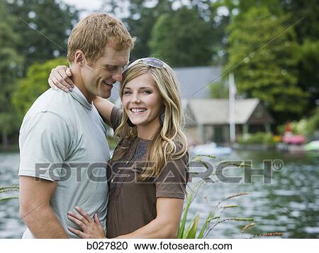 Stock Image - young couple in front of a lake. Fotosearch