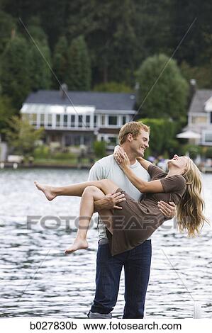 Stock Image - young couple in front of a lake. Fotosearch