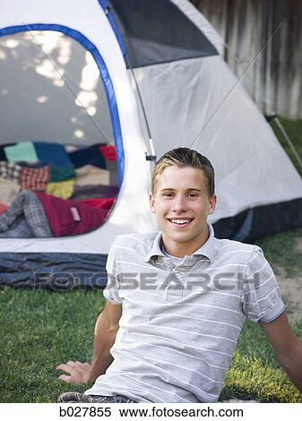 young man sitting in the backyard next to a tent View Large Photo Image Stock Photography - young man sitting in the backyard next to a tent. Fotosearch