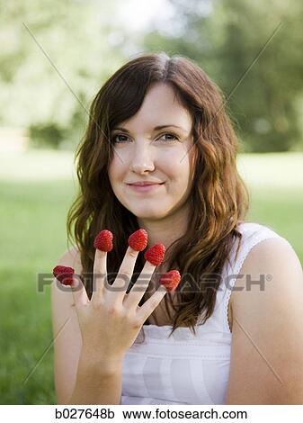 young woman eating a berry from each finger View Large Photo Image Stock Image - young woman eating a berry from each finger. Fotosearch