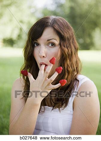 young woman eating a berry from each finger View Large Photo Image Stock Photo - young woman eating a berry from each finger. Fotosearch