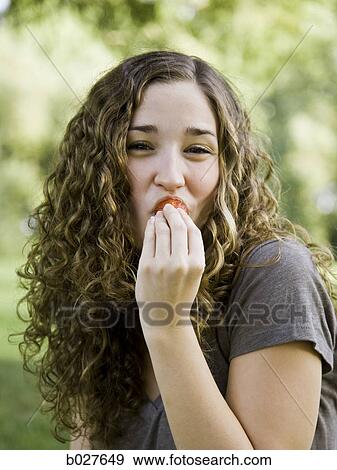 Stock Photo - young woman eating a berry. Fotosearch