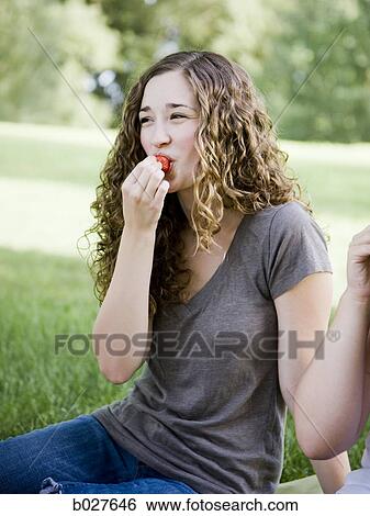 Stock Photograph - young woman eating a berry. Fotosearch