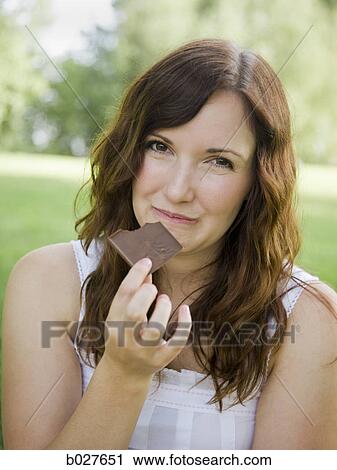 young woman eating a piece of chocolate View Large Photo Image Stock Image - young woman eating a piece of chocolate. Fotosearch