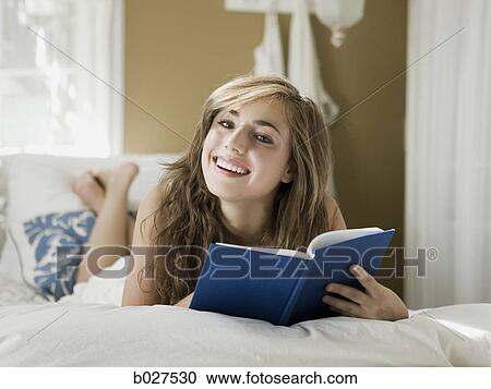 young woman lying on her bed reading a book View Large Photo Image Stock Image - young woman lying on her bed reading a book. Fotosearch