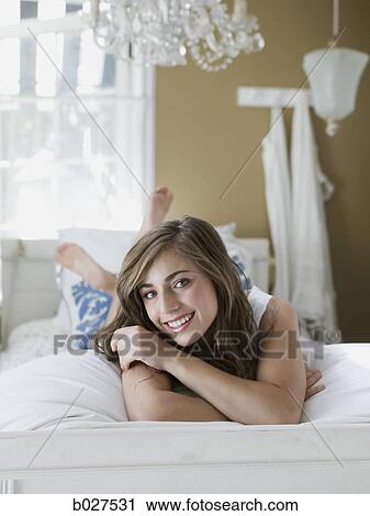 Stock Image - young woman lying on her bed. Fotosearch