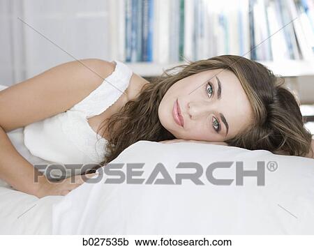 Stock Image - young woman lying on her bed. Fotosearch