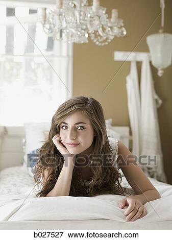 Stock Photo - young woman lying on her bed. Fotosearch