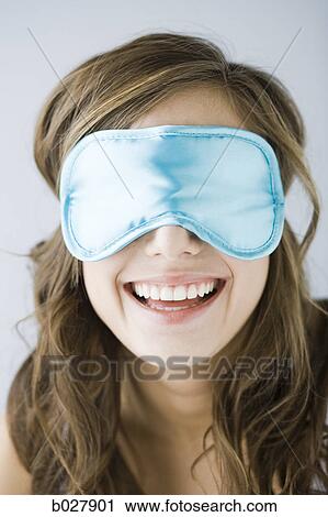 Stock Image - young woman wearing a sleeping mask. Fotosearch