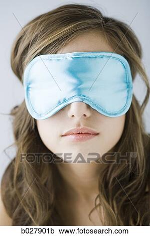Stock Image - young woman wearing a sleeping mask. Fotosearch