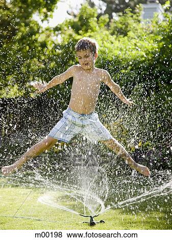 Stock Photo - boy playing in a sprinkler. Fotosearch