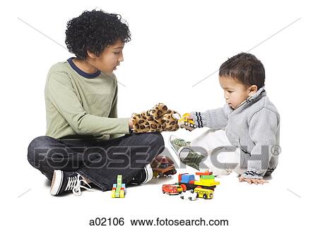 Brothers (18-23 months) (8-9) playing with toys, against white background View Large Photo Image Stock Photograph - Brothers (18-23 months) (8-9) playing with toys, against white background. Fotosearch