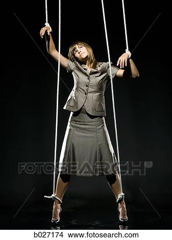 Picture - businesswoman being pulled by strings like a puppet. Fotosearch