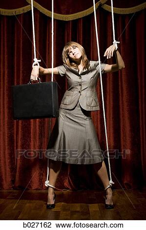 Stock Image - businesswoman being pulled by strings like a puppet. Fotosearch