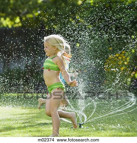 Picture - children playing in a sprinkler. Fotosearch