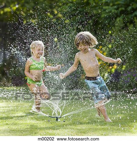 Stock Image - children playing in a sprinkler. Fotosearch