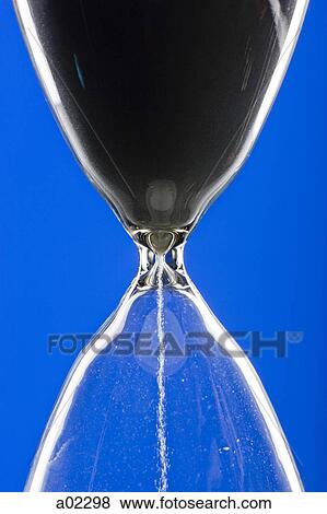 Close-up of hourglass on blue background View Large Photo Image Stock Photo - Close-up of hourglass on blue background. Fotosearch