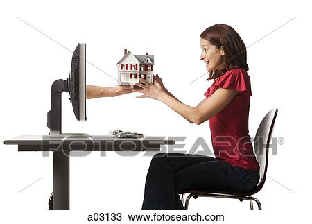 Stock Image - Conceptual picture of young woman receiving house out of her computer. Fotosearch