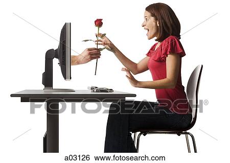 Stock Photograph - Conceptual picture of young woman receiving red rose out of her computer. Fotosearch