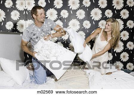 Stock Photo - couple having a pillow fight in bed. Fotosearch