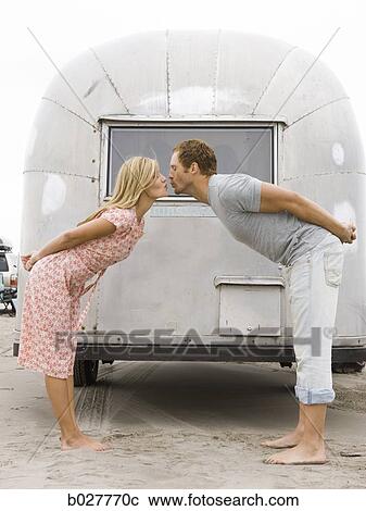 Stock Image - couple in front of their airstream classic trailer. Fotosearch