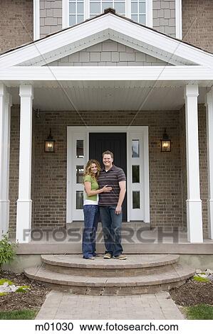Stock Image - couple standing in front of house. Fotosearch