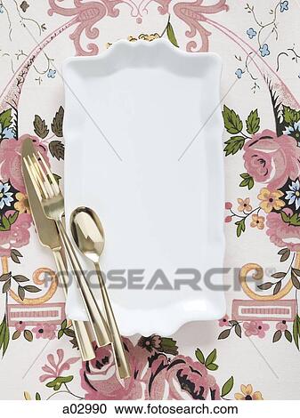 Stock Image - Empty plate with golden utensils on floral pattern. Fotosearch