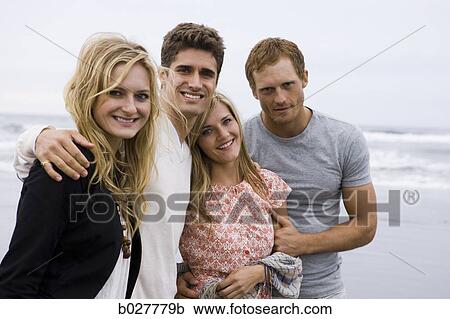 four people standing on the beach with their arms around each other View Large Photo Image Stock Image - four people standing on the beach with their arms around each other. Fotosearch