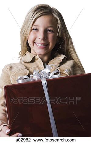 Stock Image - Girl (10--11) standing with gift, portrait. Fotosearch